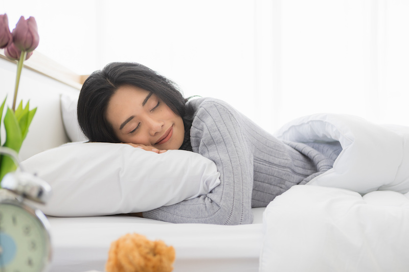 Woman enjoying laying down in her bed, feeling content and tired