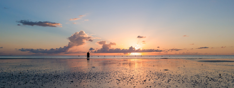Couple on beach watching beautiful sunrise