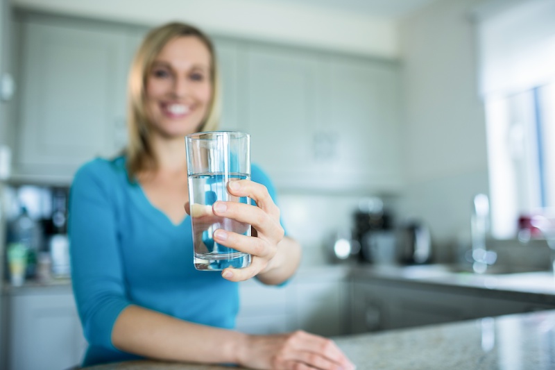 Woman drinking water in her kitchen