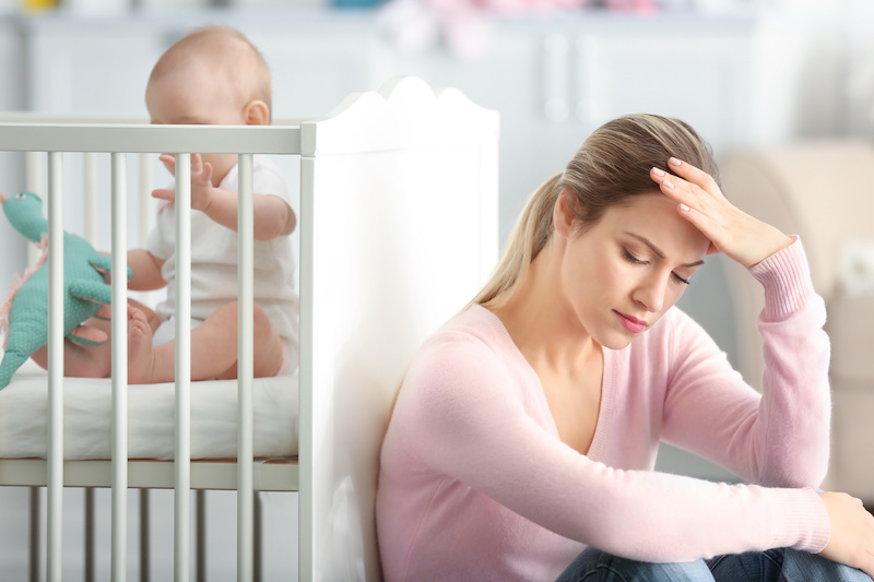 Mother with baby in crib dealing with post party depression