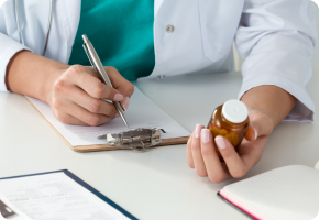 Person writing with medication bottle